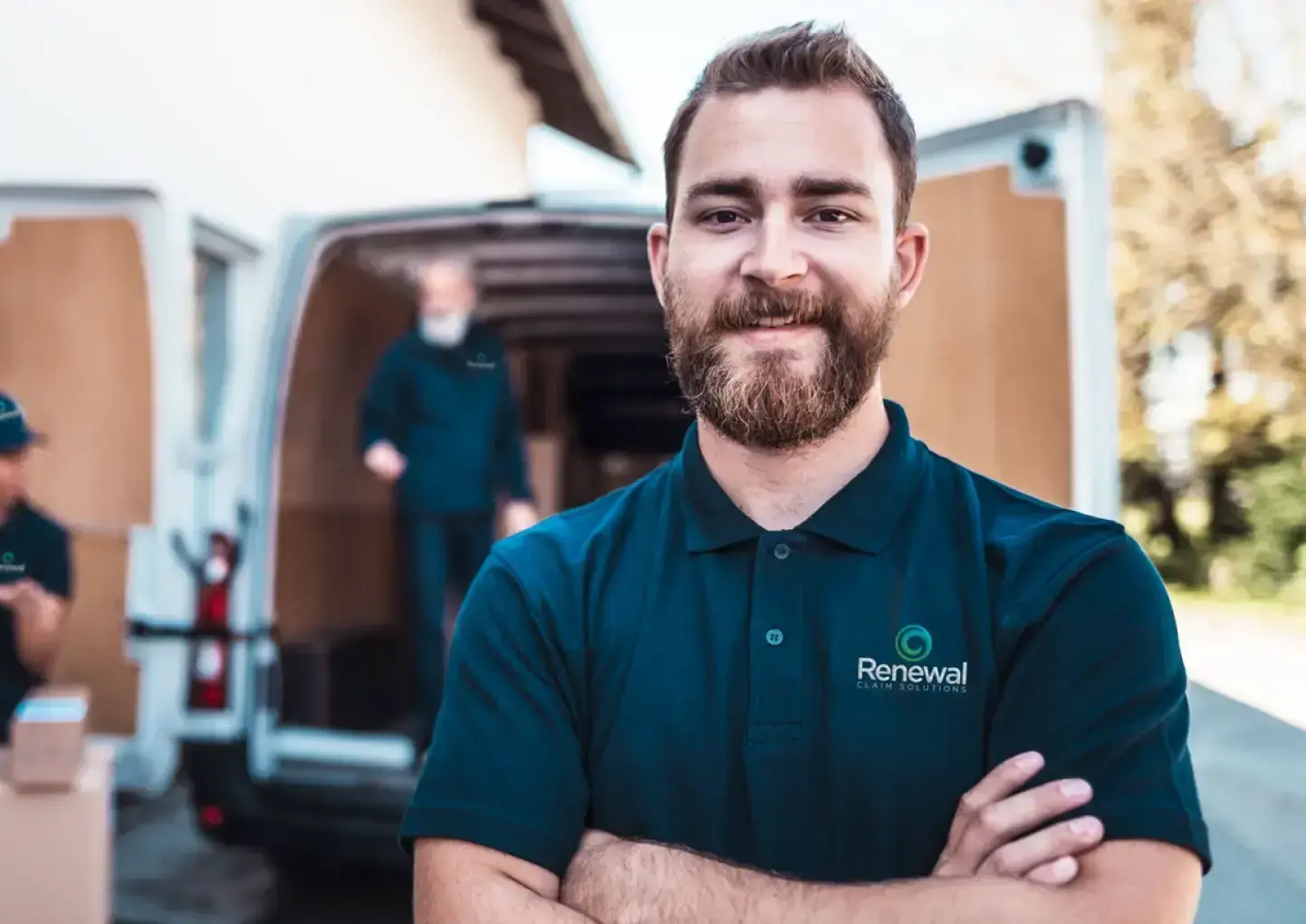 A smiling Renewal employee stands in front of a branded Renewal van after providing fire damage clean up services.